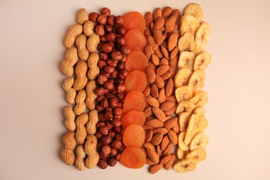 Photo of Mix of delicious dried nuts and fruits on beige background, flat lay