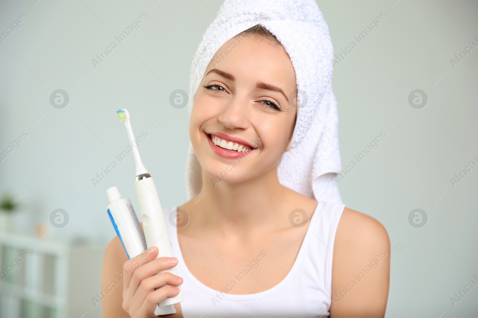 Photo of Portrait of young woman with electric toothbrush and paste on blurred background