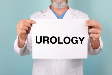 Photo of Male doctor holding paper with word UROLOGY on color background