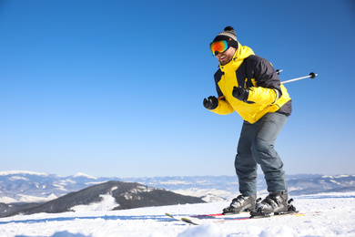 Photo of Young man skiing on hill, space for text. Winter vacation