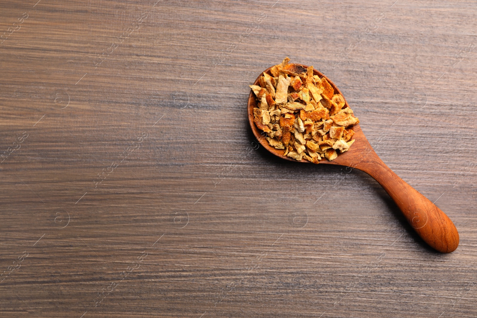 Photo of Spoon with dried orange zest seasoning on wooden table, top view. Space for text