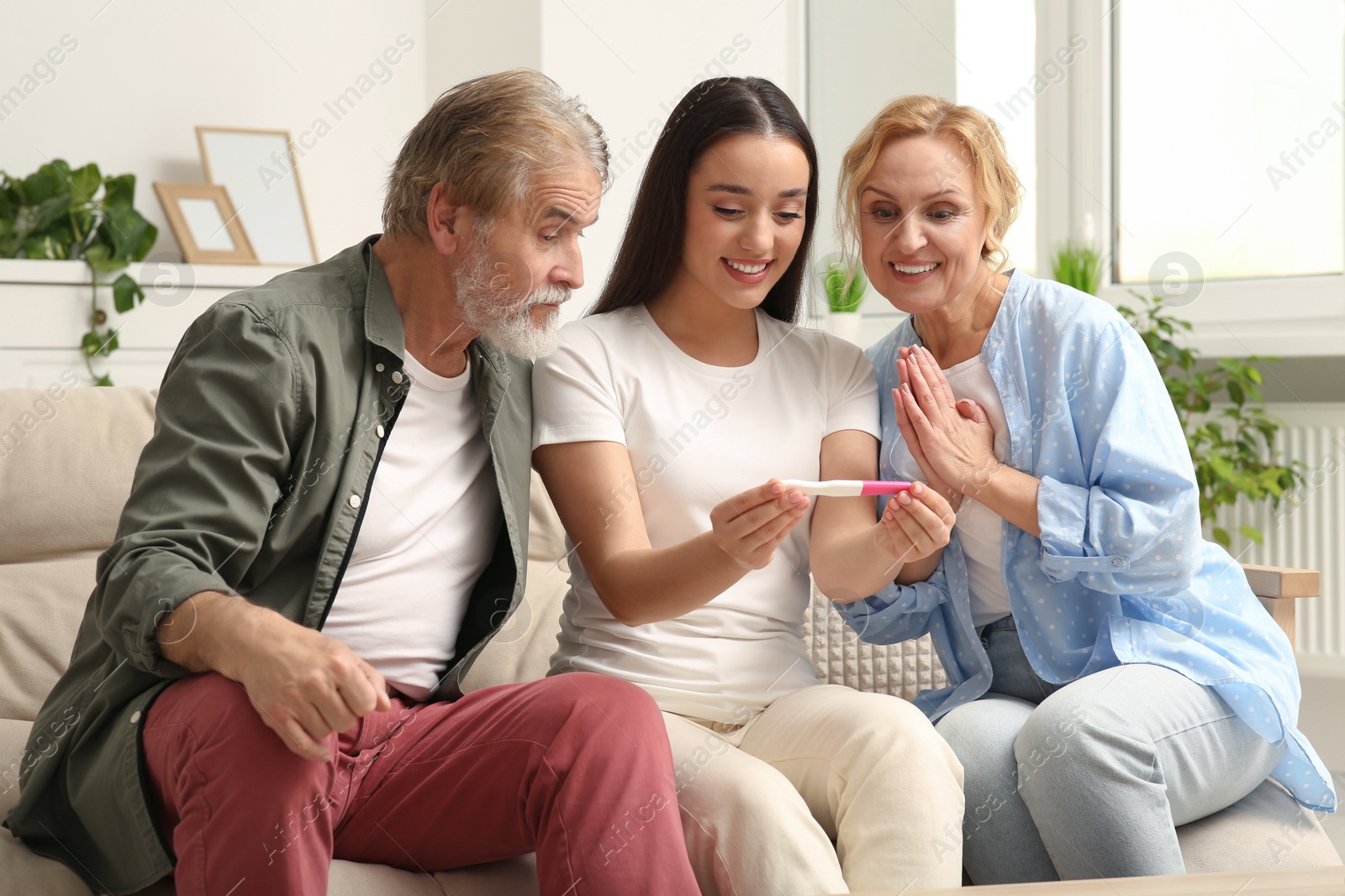 Photo of Happy woman showing her parents pregnancy test at home. Grandparents' reaction to future grandson