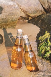 Photo of Bottles of cold beer near rock on sandy beach