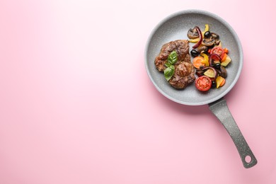 Photo of Tasty fried steak with vegetables in pan on pink background, top view. Space for text