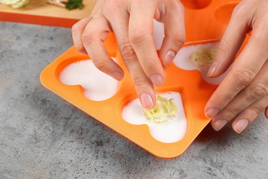 Woman making natural handmade soap at grey stone table, closeup