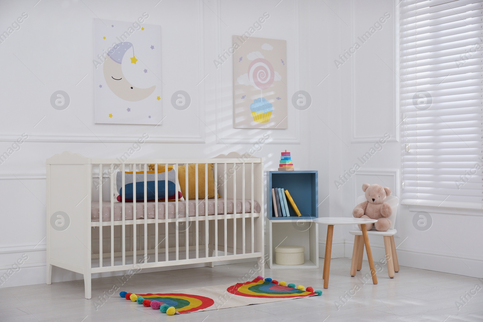 Photo of Cute baby room interior with comfortable crib and pictures