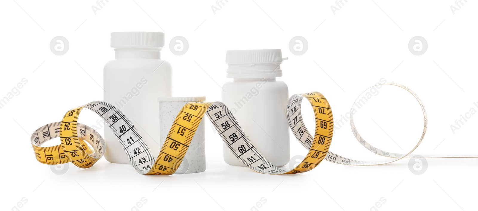 Photo of Bottles of weight loss pills and measuring tape isolated on white