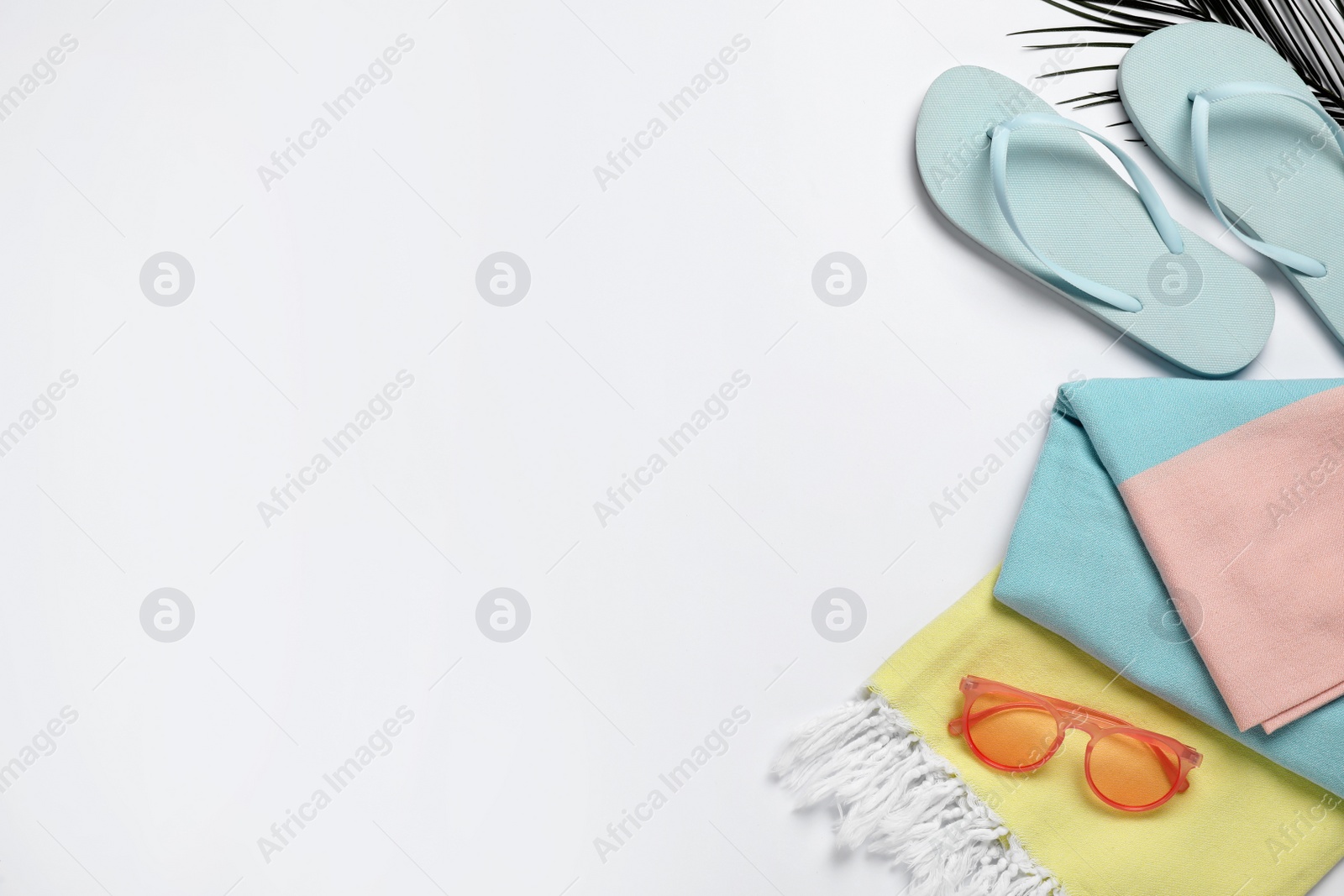 Photo of Beach towel, flip flops and sunglasses on white background, flat lay. Space for text