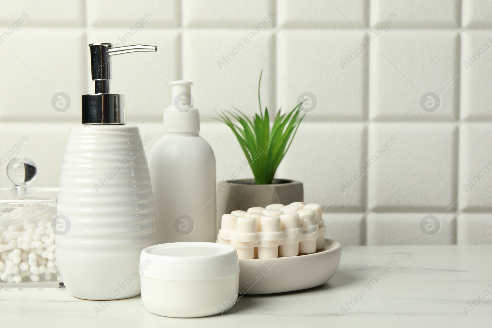 Photo of Different bath accessories and personal care products on white table near tiled wall