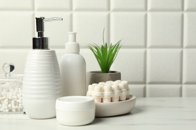 Different bath accessories and personal care products on white table near tiled wall