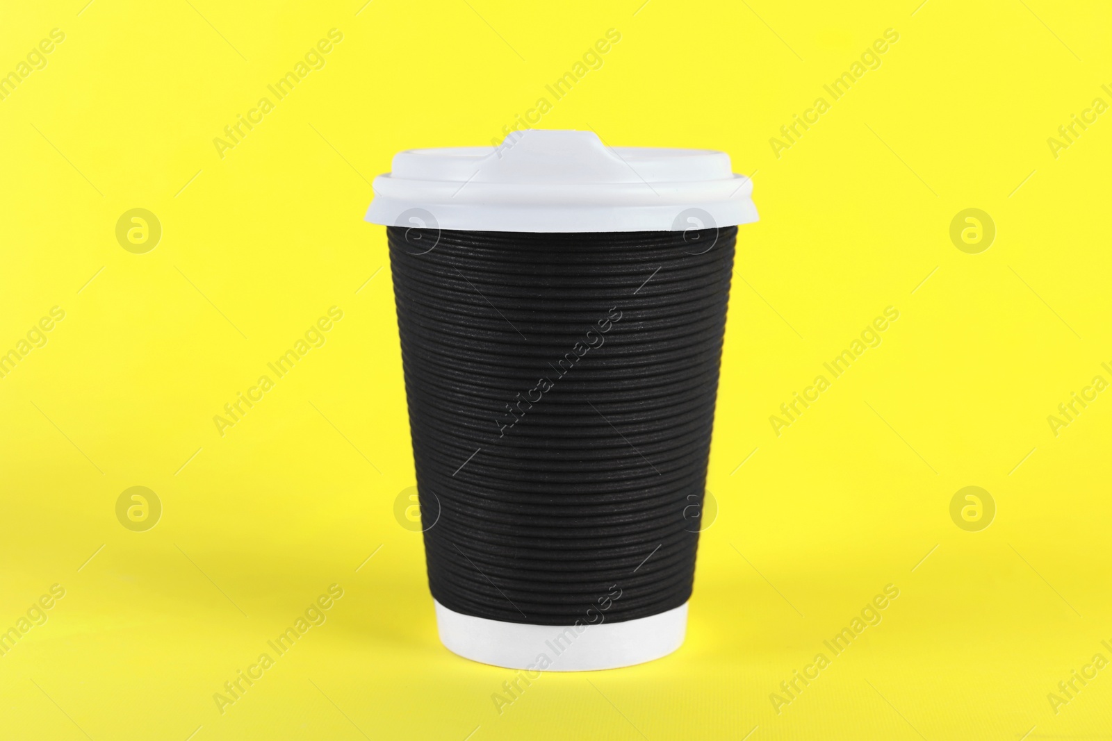 Photo of Black paper cup with plastic lid on yellow background. Coffee to go