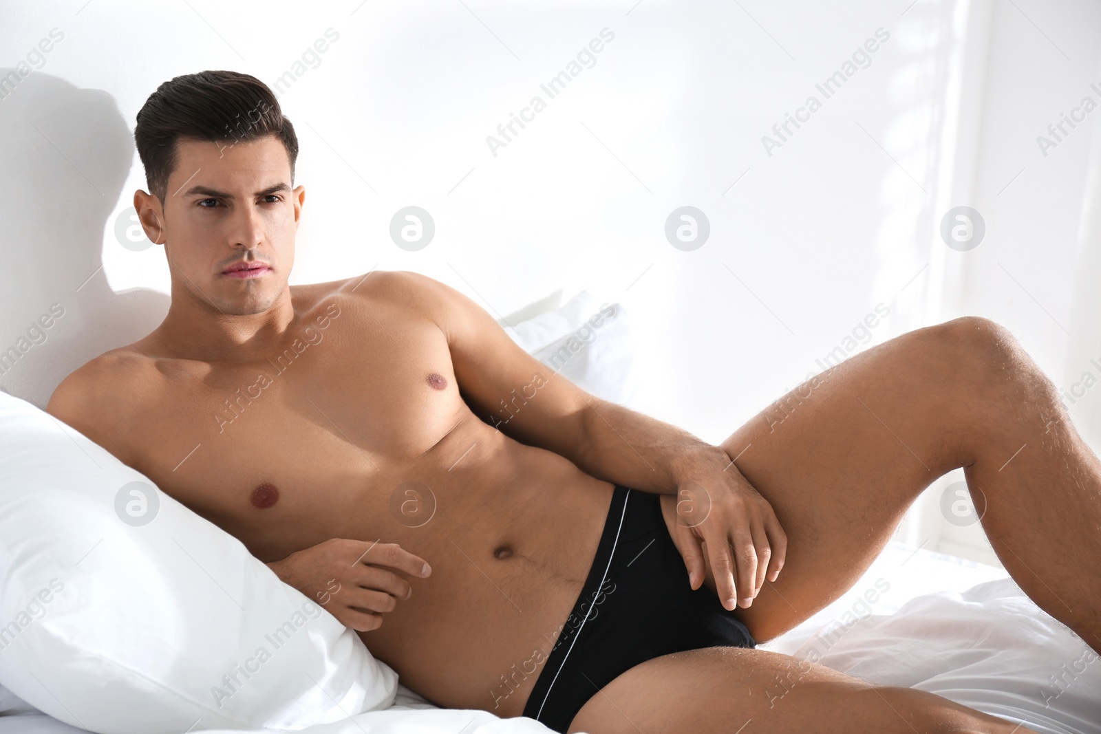Photo of Handsome man in black underwear on bed indoors