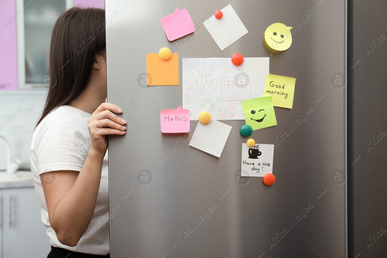 Photo of Woman opening refrigerator door with paper sheets and magnets at home, closeup