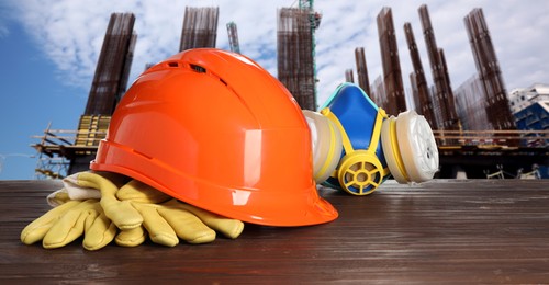 Image of Safety equipment and tools on wooden surface and blurred view of construction site. Banner design