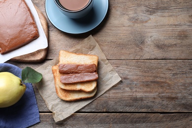 Photo of Tasty sandwich with quince paste served for breakfast on wooden table, flat lay. Space for text