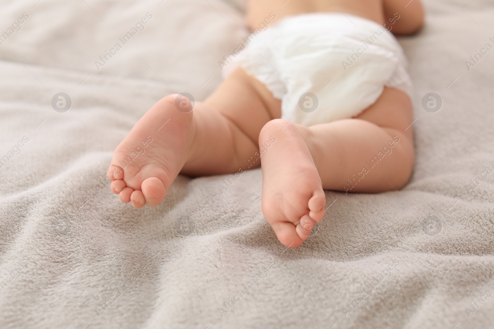 Photo of Cute little baby lying on bed, closeup of legs