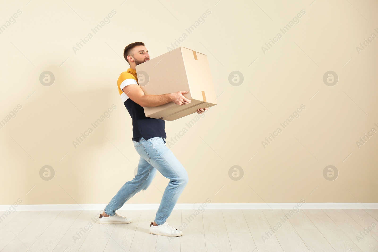 Photo of Full length portrait of young man carrying carton box near color wall. Posture concept