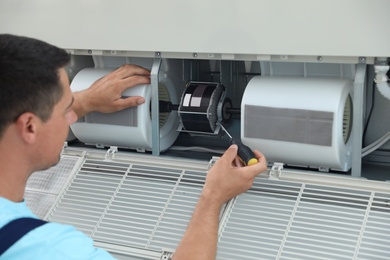 Photo of Technician repairing and checking air conditioner indoors