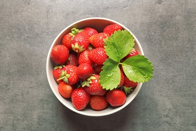 Bowl with ripe strawberries on grey background, top view