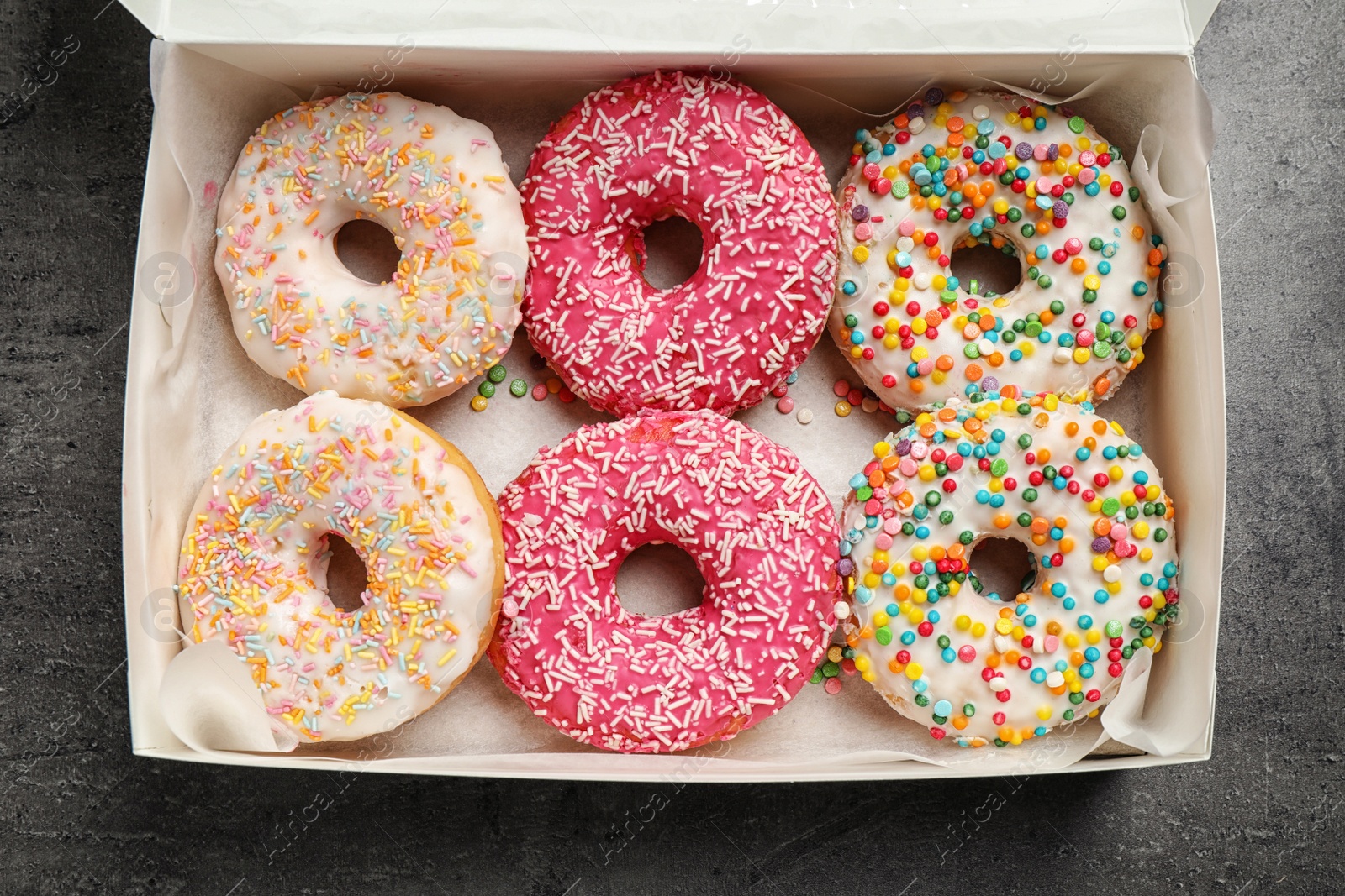 Photo of Delicious glazed donuts on grey table, top view