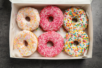Photo of Delicious glazed donuts on grey table, top view