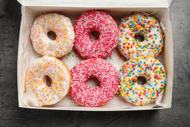 Delicious glazed donuts on grey table, top view