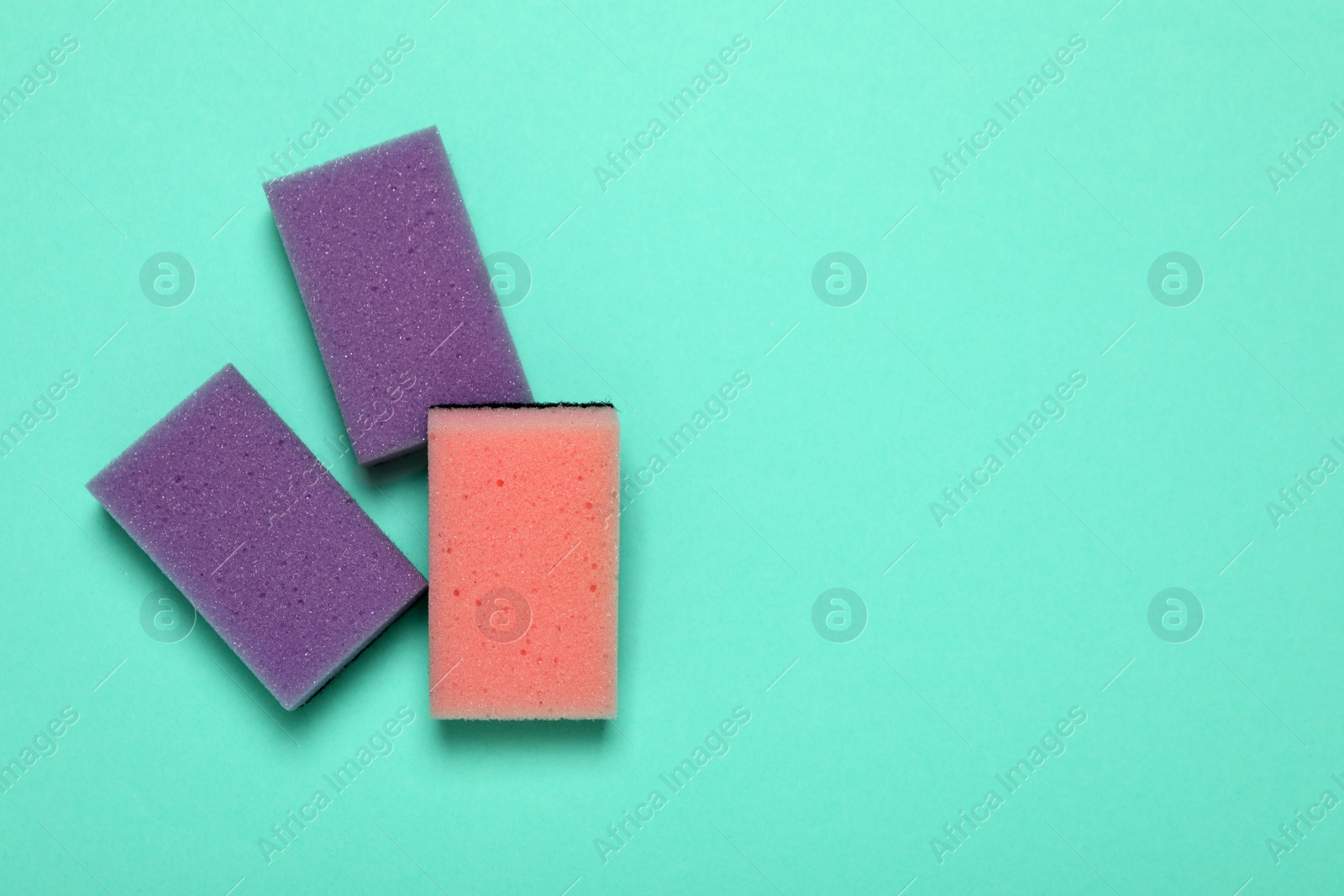 Photo of Three sponges on turquoise background, flat lay. Space for text