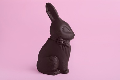 Photo of Dark chocolate bunny on pink background. Easter celebration