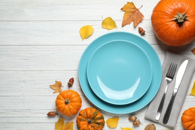 Photo of Flat lay composition with tableware, pumpkins and autumn leaves on white wooden background, space for text. Thanksgiving Day