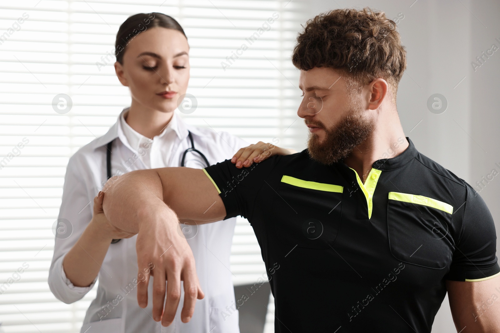 Photo of Sports injury. Doctor examining patient's shoulder in hospital