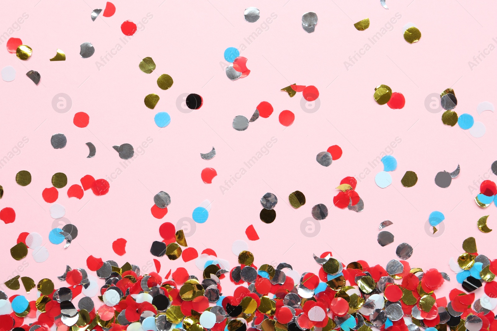 Photo of Shiny colorful confetti on light pink background, flat lay