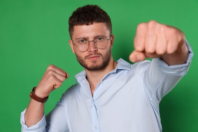 Photo of Young man ready to fight on green background