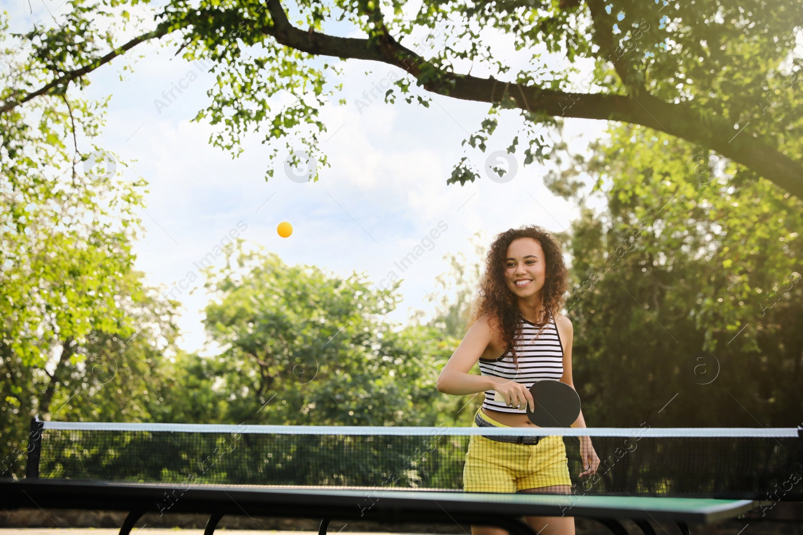 Photo of Young African-American woman playing ping pong outdoors