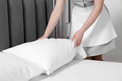 Photo of Maid making bed in hotel room, closeup