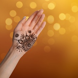 Image of Woman with henna tattoo on palm against blurred lights, bokeh effect