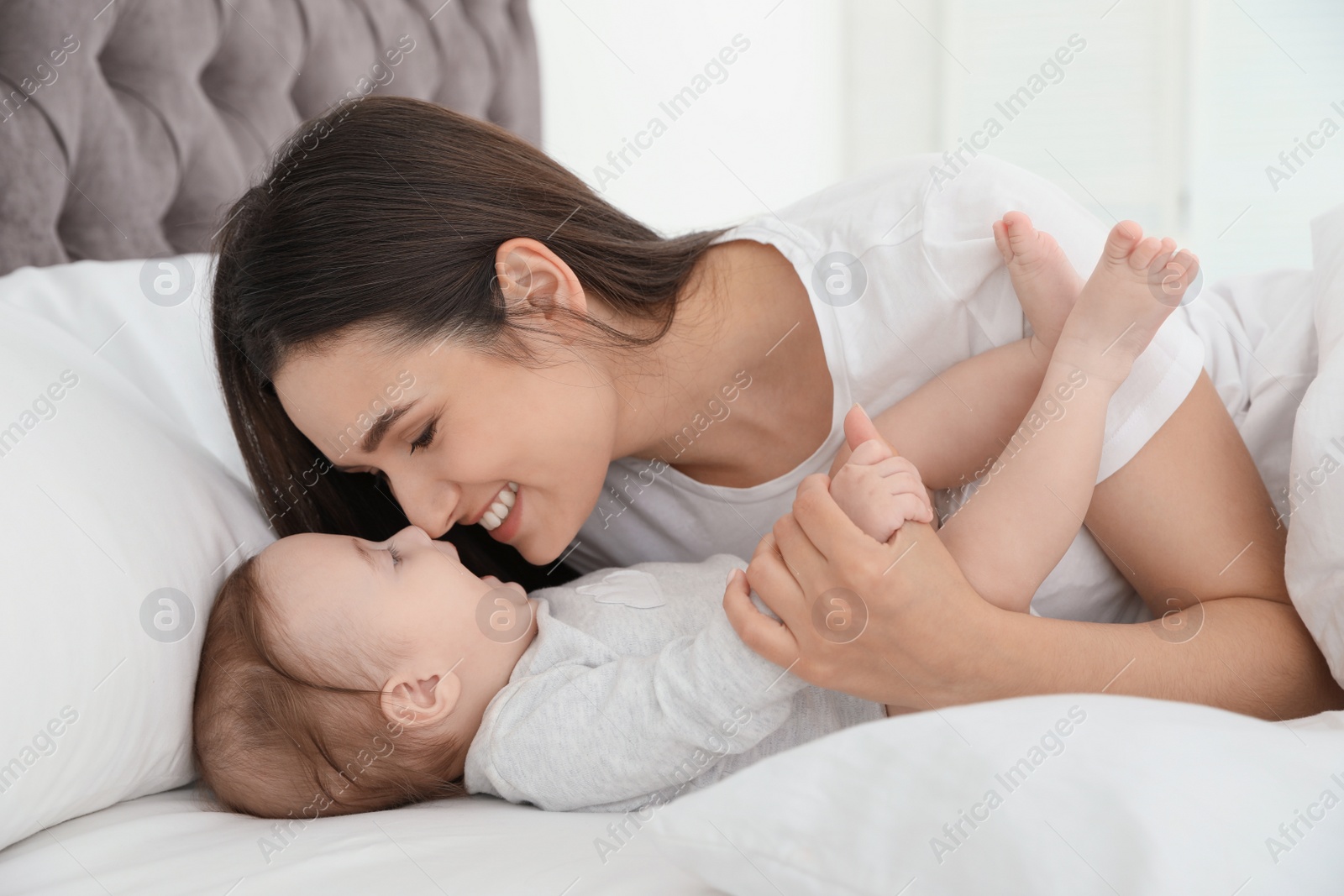 Photo of Portrait of mother with her cute baby lying on bed indoors