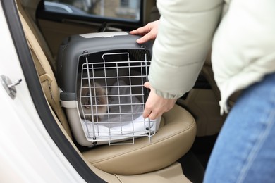 Photo of Woman closing pet carrier with cat in car, closeup
