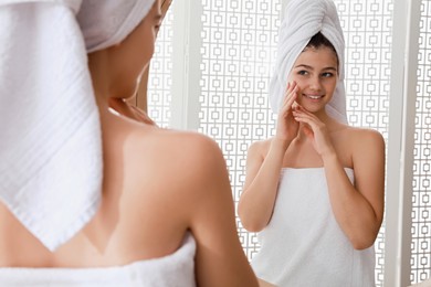 Photo of Beautiful teenage girl with towels near mirror in bathroom
