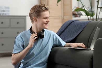 Photo of Online learning. Smiling teenage boy near laptop at home