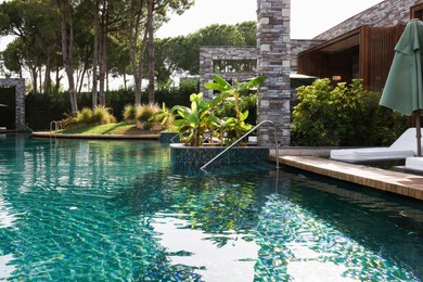 Swimming pool, metal rail and tropical plants at luxury resort