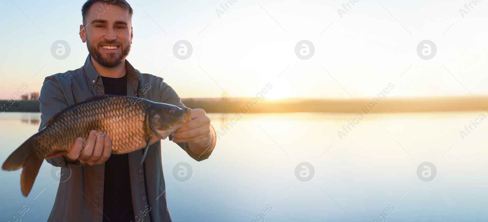 Image of Fisherman holding caught fish at riverside, space for text. Banner design