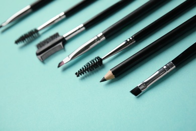 Photo of Set of professional eyebrow tools on turquoise background