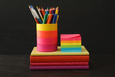 Photo of Different school stationery on stone table near blackboard. Back to school