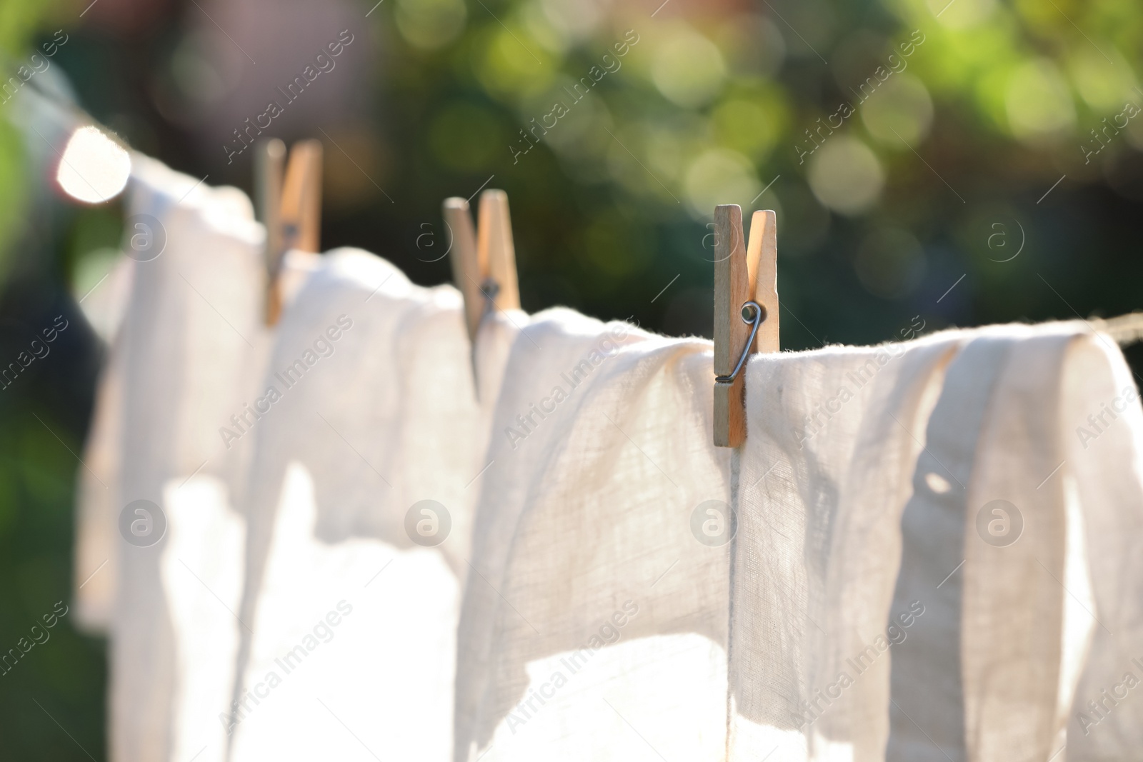 Photo of Washing line with drying shirt against blurred background, focus on clothespin