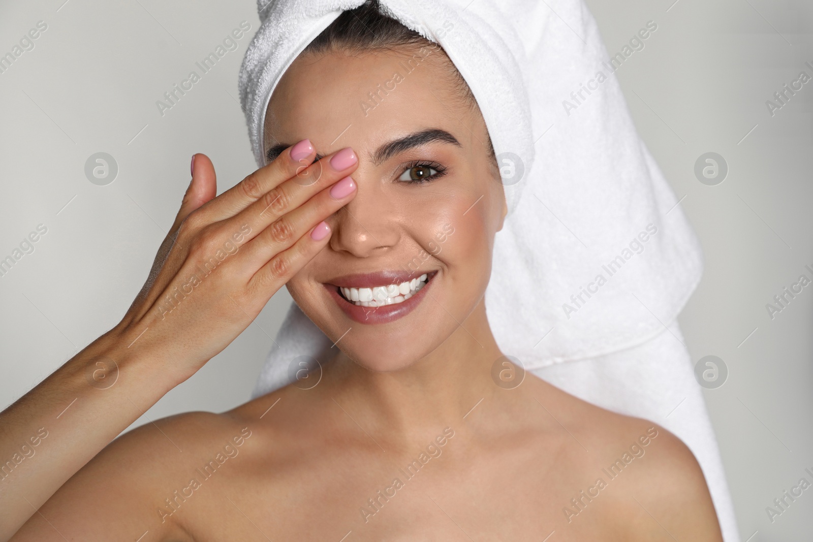 Photo of Beautiful young woman with towel on head against light background