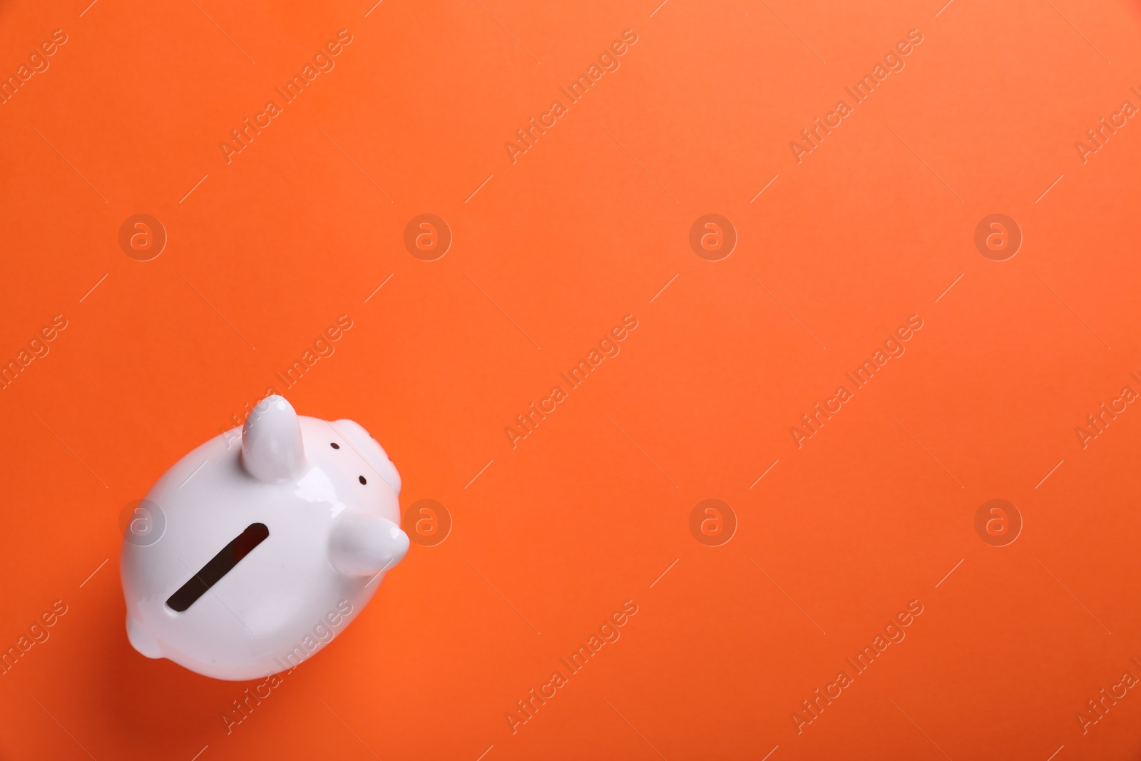 Photo of Ceramic piggy bank on orange background, top view with space for text. Financial savings