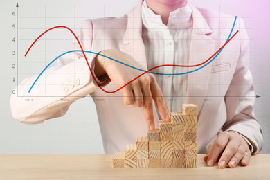 Image of Finance trading concept. Woman with wooden blocks at table and chart, closeup