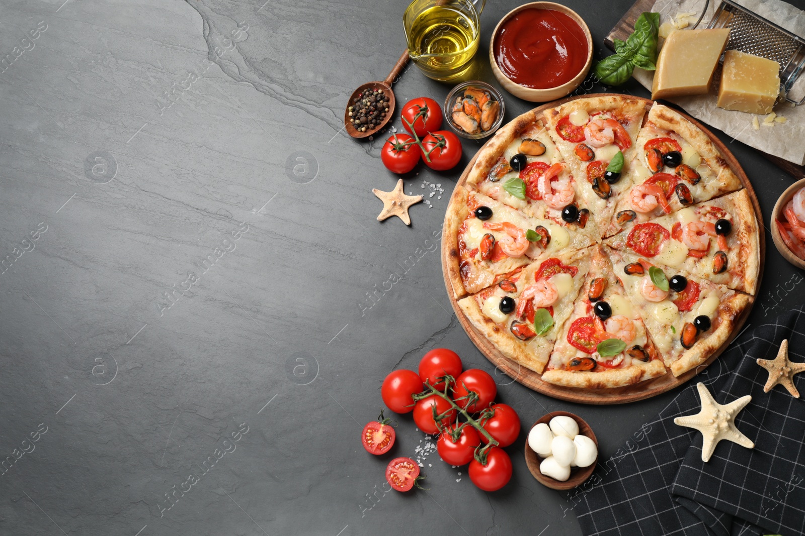 Photo of Tasty pizza with seafood and ingredients on black table, flat lay. Space for text