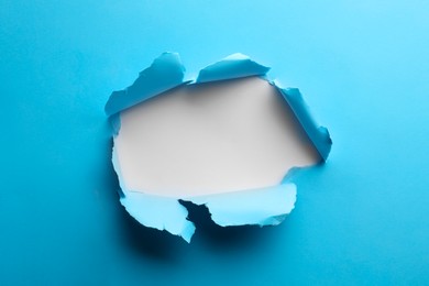 Photo of Hole in light blue paper on white background