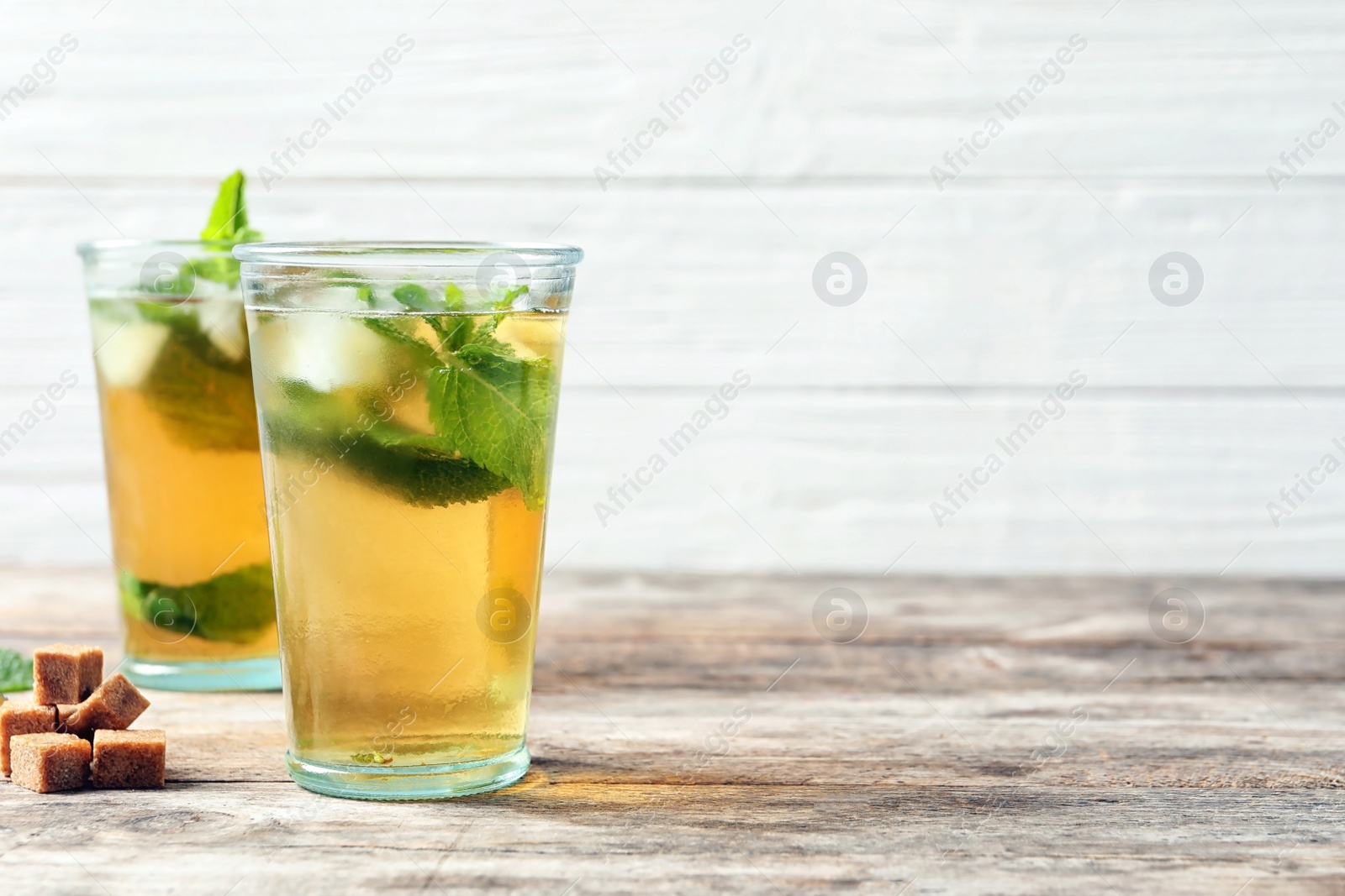 Photo of Glasses with aromatic mint tea, fresh leaves and sugar cubes on wooden table